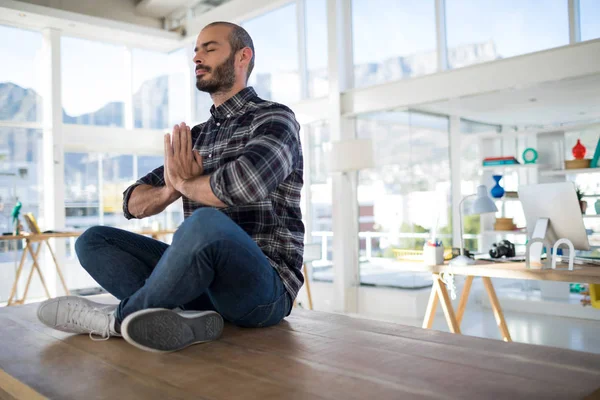 Manliga verkställande utför yoga på ett bord — Stockfoto