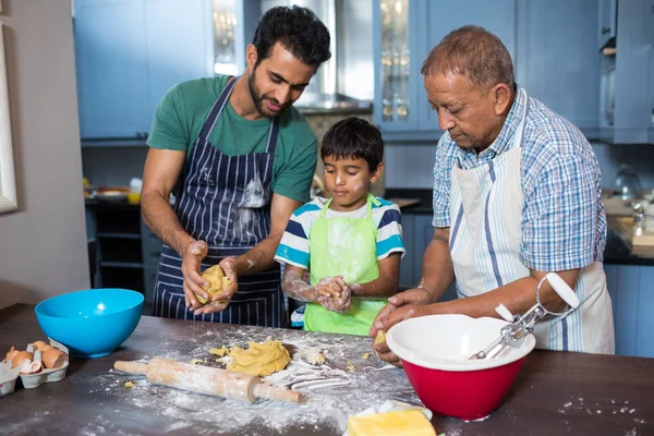 Família segurando massa enquanto prepara comida — Fotografia de Stock