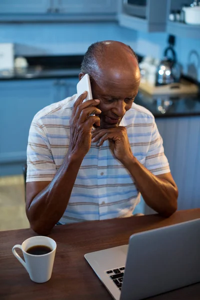 Homem falando no telefone ao usar o portátil — Fotografia de Stock