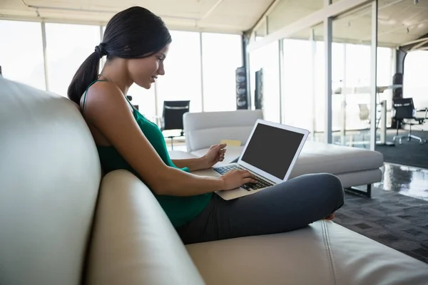 Vrouw met laptop op sofa op kantoor — Stockfoto