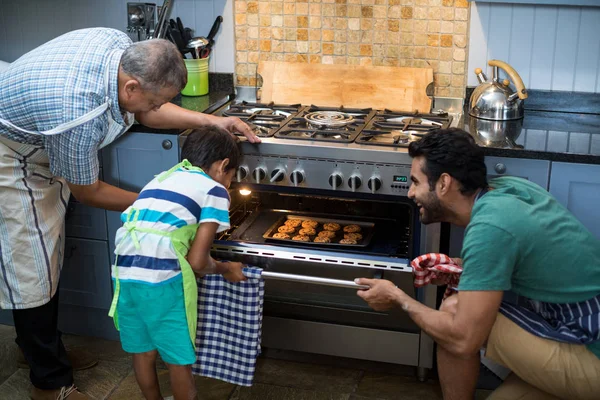 Família mantendo biscoitos no forno — Fotografia de Stock
