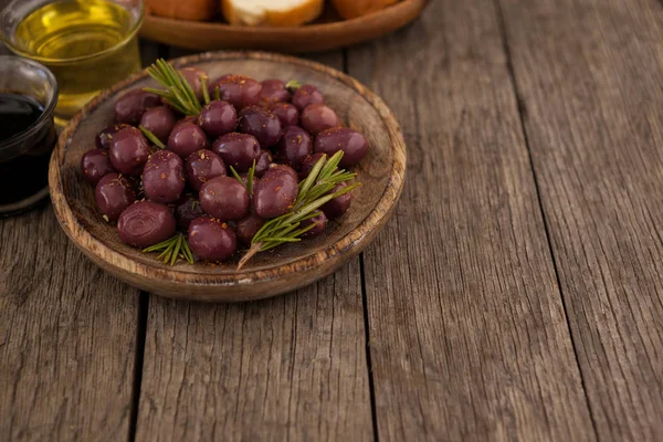 Olives with herb in wooden plate — Stock Photo, Image