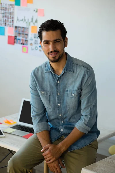 Man sitting on desk at office — Stock Photo, Image