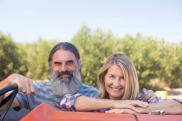 Ehepaar steht neben Traktor in Olivenbauernhof — Stockfoto