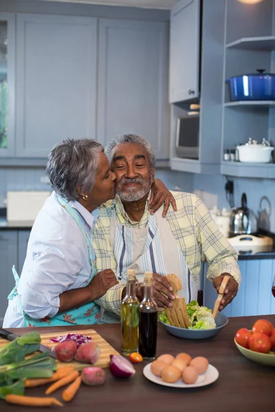 Frau küsst Mann beim Zubereiten von Essen — Stockfoto