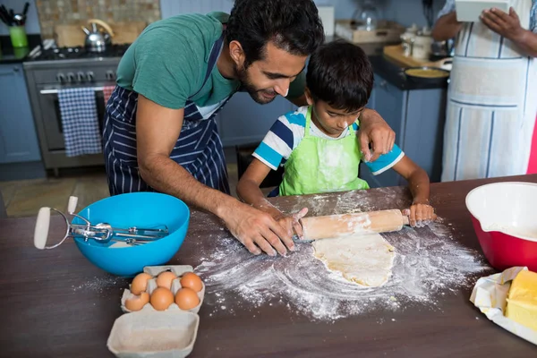 Father assisting son for rolling dough — Stock Photo, Image