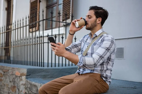 Человек выпивает во время пользования телефоном — стоковое фото