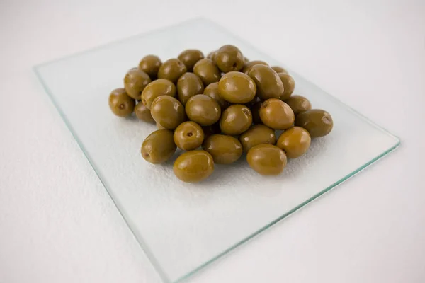 Зеленые оливки на стеклянной плите — стоковое фото