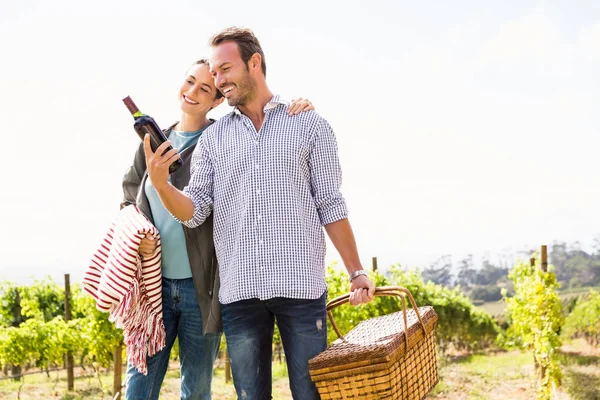 Hombre con mujer sosteniendo botella de vino y cesta — Foto de Stock