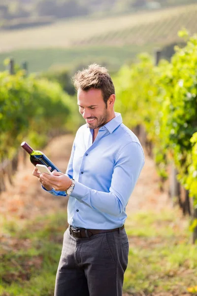 Uomo con bottiglia di vino utilizzando il telefono — Foto Stock