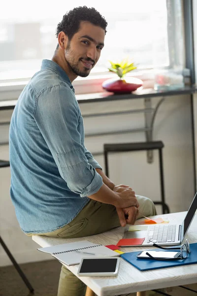 Man sitting on desk in office — Stock Photo, Image