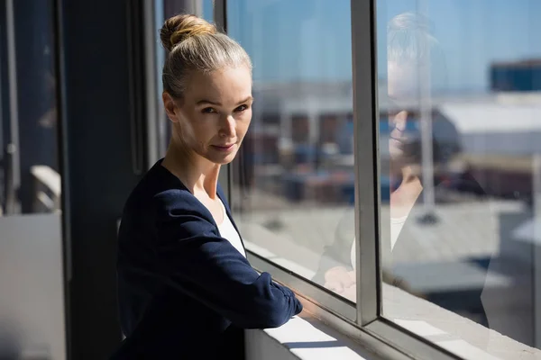 Уверенная женщина, стоящая у окна в офисе — стоковое фото