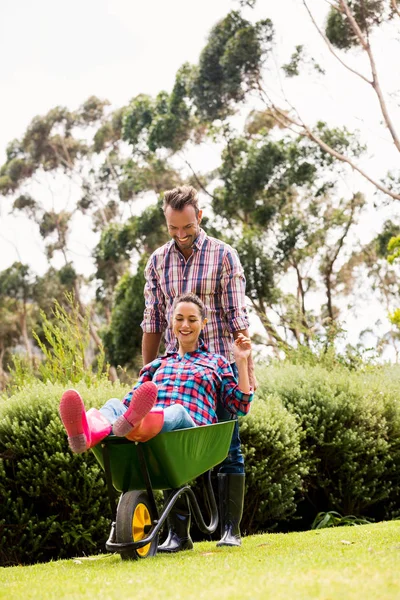 Man pushing young woman in wheelbarrow — Stock Photo, Image