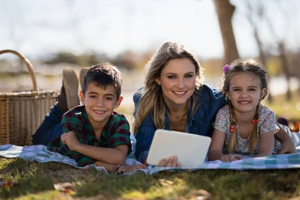 Madre e hijos sosteniendo la tableta en el parque —  Fotos de Stock