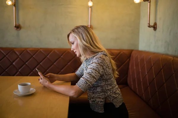 Kobieta przy użyciu telefonu komórkowego w tabeli — Zdjęcie stockowe