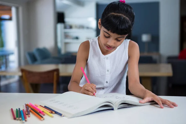 Chica dibujo en el libro en el mostrador — Foto de Stock