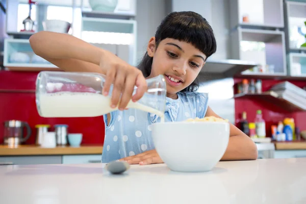 Chica vertiendo leche en el tazón del desayuno — Foto de Stock