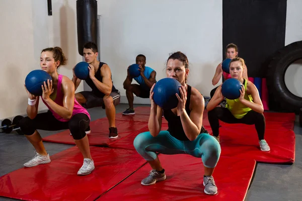 Спортсмены, приседающие с мячами для упражнений — стоковое фото