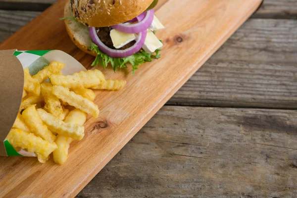 Pommes frites och hamburgare på skärbräda — Stockfoto