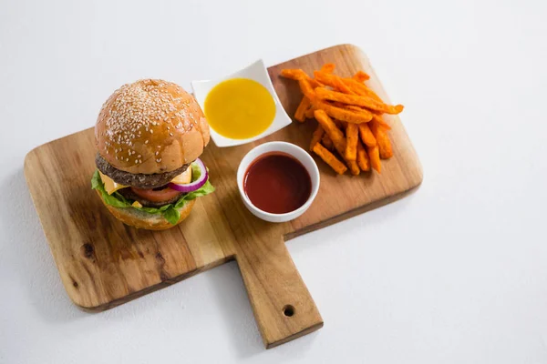 Francouzské hranolky a burger na prkénku — Stock fotografie