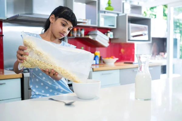 Flicka hälla frukostflingor i skål — Stockfoto