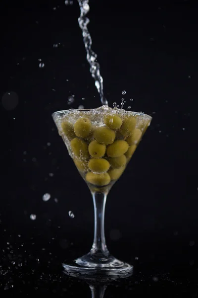 Martini splashing into glass with olives — Stock Photo, Image