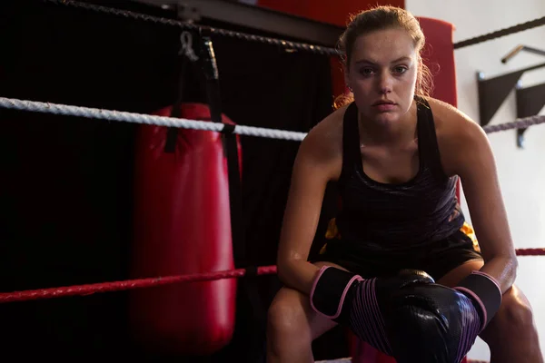 Confident woman sitting in boxing ring — Stock Photo, Image