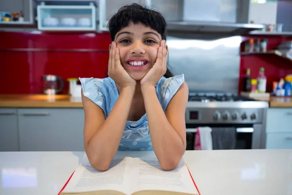 Chica sentada con novela en cocina —  Fotos de Stock