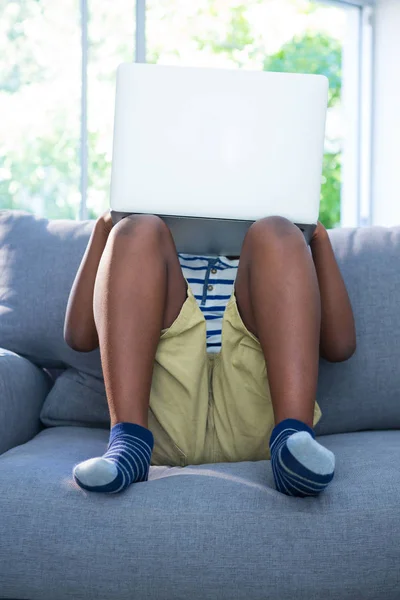 Pojken sitter på soffan och använder bärbar dator — Stockfoto