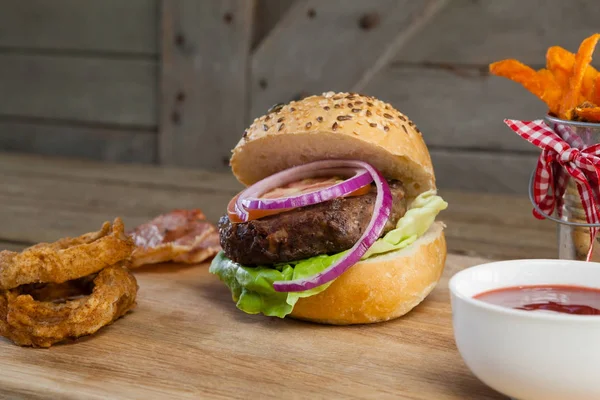 Hamburger z krążkami cebuli i sosem pomidorowym — Zdjęcie stockowe