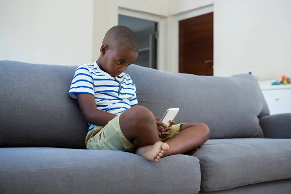 Chłopiec przy użyciu telefonu komórkowego na kanapie — Zdjęcie stockowe