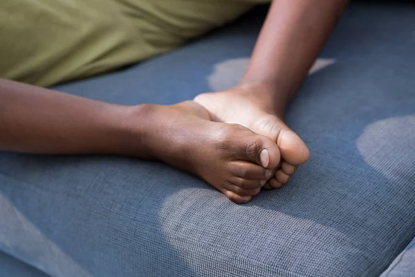 Garçon joignant les pieds tout en étant assis sur canapé — Photo