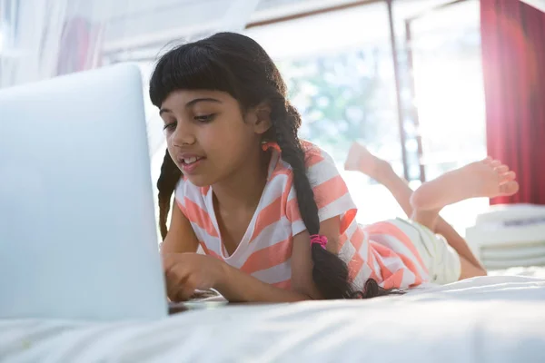 Κορίτσι πληκτρολογώντας το laptop στο κρεβάτι — Φωτογραφία Αρχείου