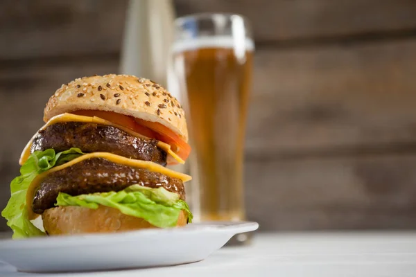 Hambúrguer em prato e copo de cerveja — Fotografia de Stock