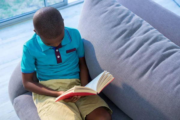 Niño leyendo novela en sofá —  Fotos de Stock