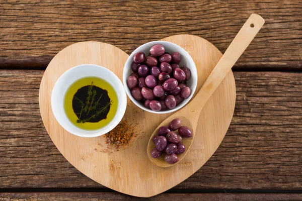 Пурпурные оливки с маслом и деревянной ложкой — стоковое фото