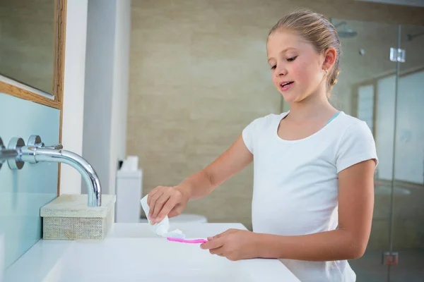 Girl removing toothpaste on brush — Stock Photo, Image