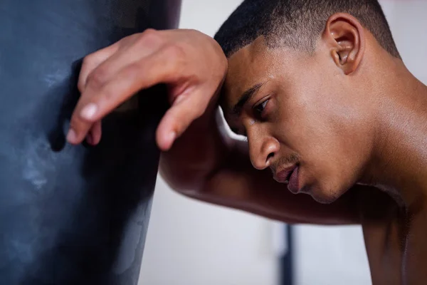 Triste hombre apoyado en el saco de boxeo — Foto de Stock