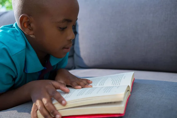 Niño leyendo novela en sofá — Foto de Stock