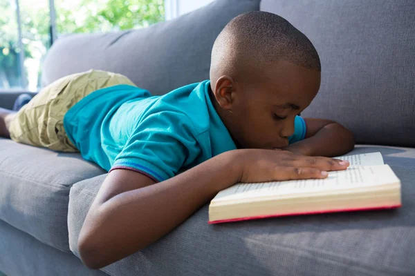 Pojke läsa romanen på soffa — Stockfoto