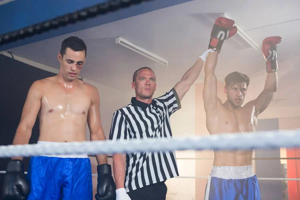 Referee holding hands of winning boxer