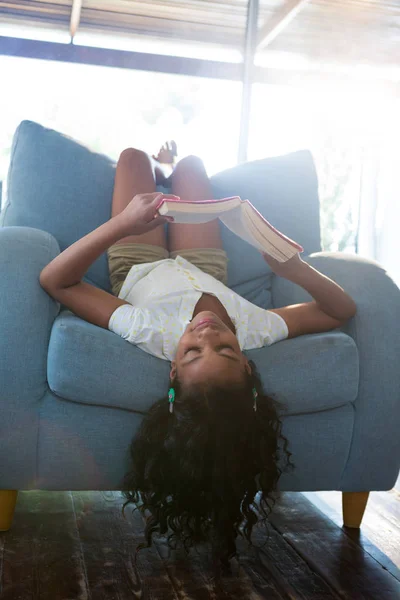 女孩看书在扶手椅上 — 图库照片