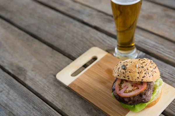 Hamburguesa sobre tabla de cortar y cerveza — Foto de Stock