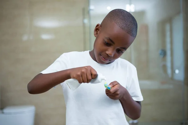 Мальчик удаляет зубную пасту на щетке — стоковое фото