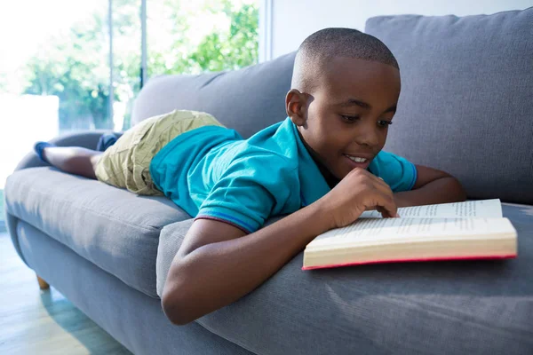 Sonriente niño leyendo novela Imagen de stock