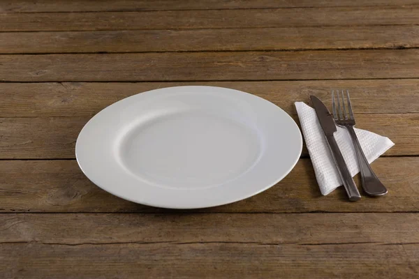 Белая тарелка со столовыми приборами и салфеткой — стоковое фото