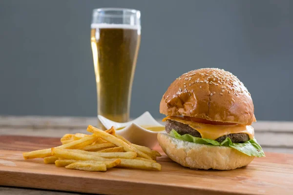 Cheeseburger com batatas fritas e um copo de cerveja — Fotografia de Stock