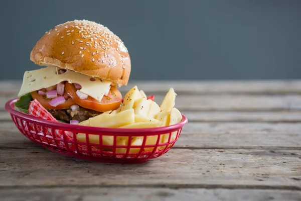 Cheeseburger e batatas fritas em cesto — Fotografia de Stock