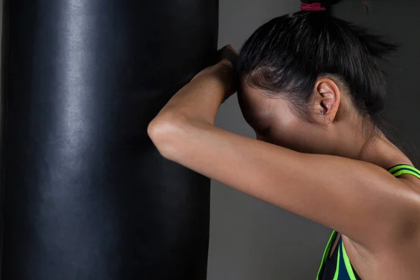 Boxeador femenino apoyado en saco de boxeo —  Fotos de Stock