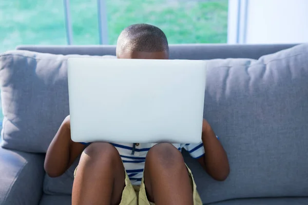 Jongen met behulp van laptop op sofa — Stockfoto